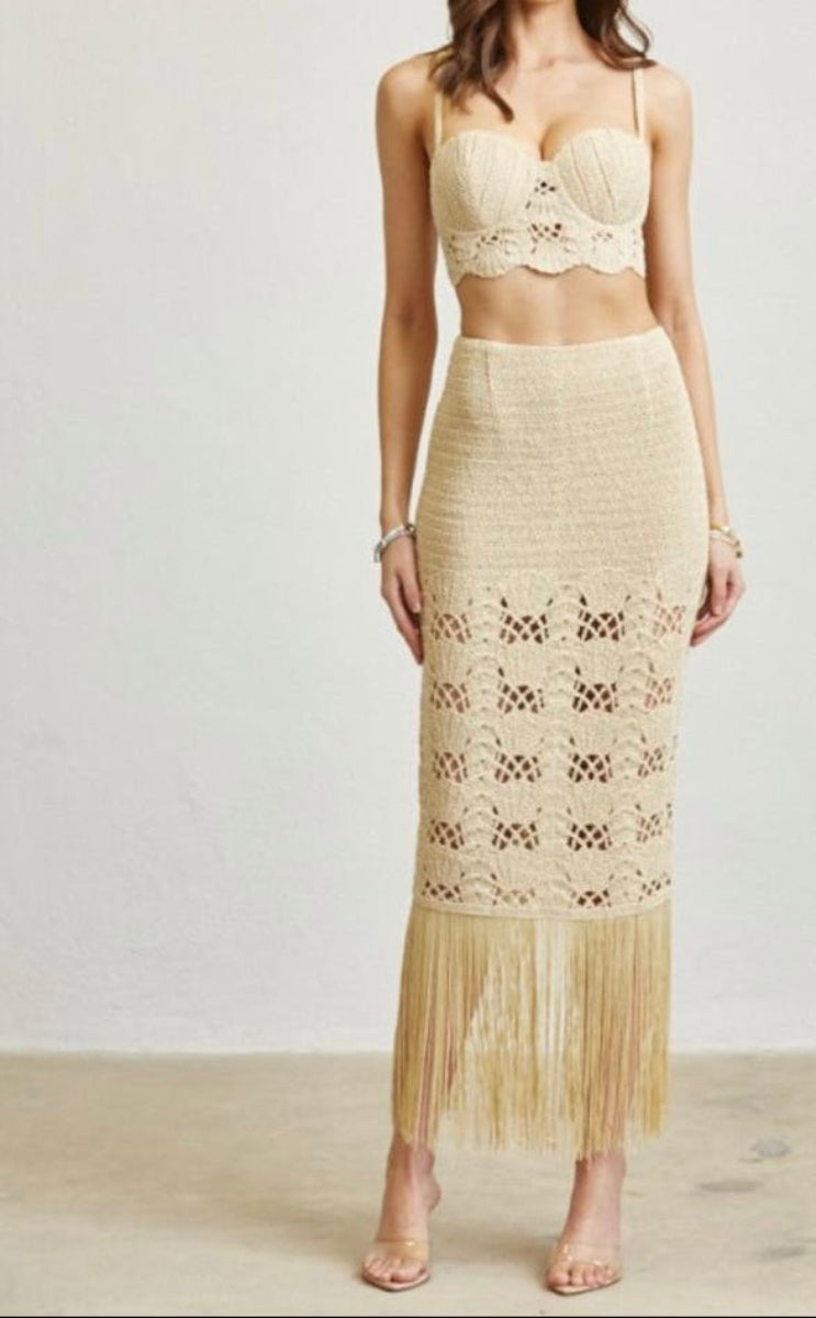 Woman wearing a beige lace top and skirt set on a plain background