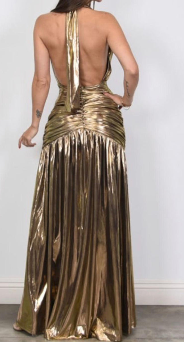 Woman wearing a gold halter neck dress with a plain background