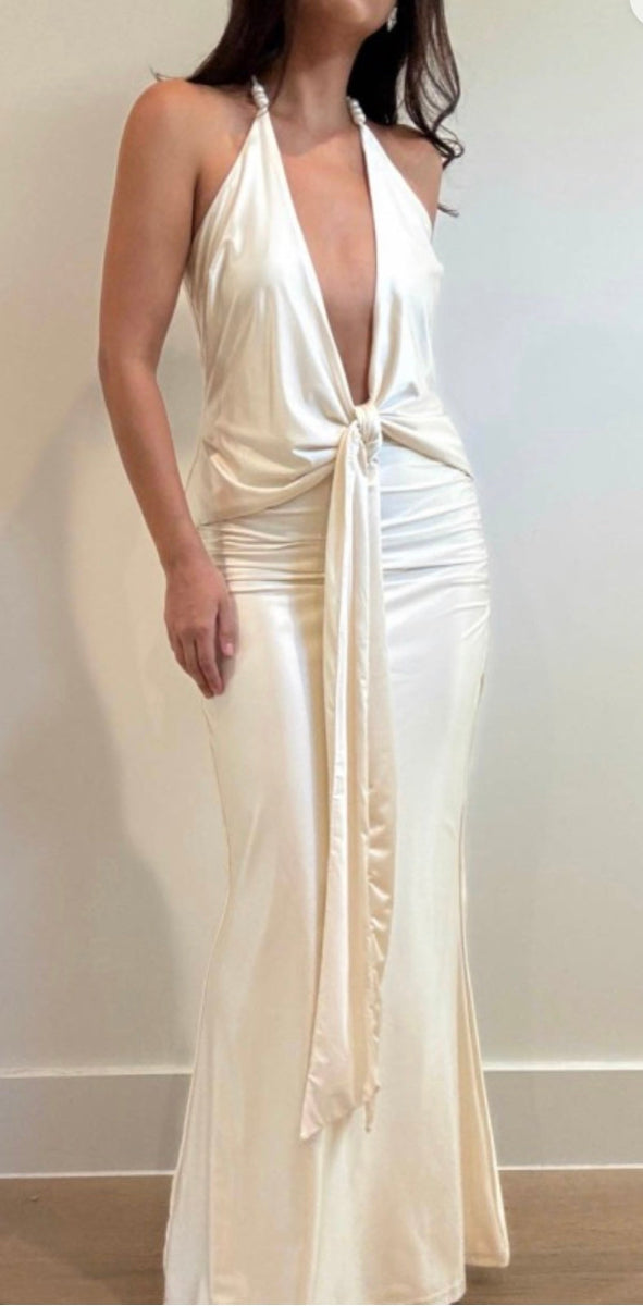 Woman wearing a white plunge neck dress with a deep neckline against a plain background