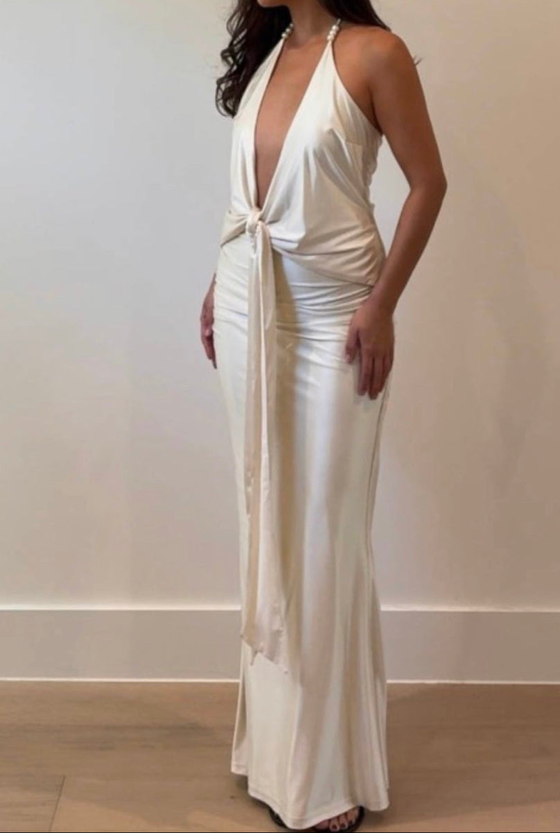 Woman wearing a white halter neck dress against a plain background